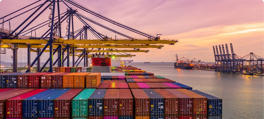 Container terminal at sunset with stacked containers and gantry cranes