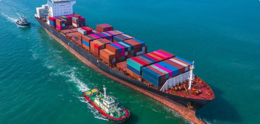 Loaded container vessel leaving port escorted by a tug